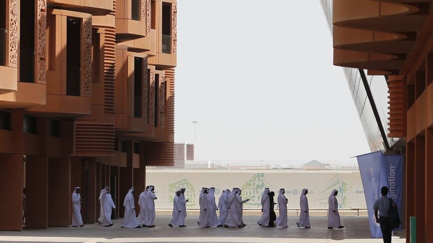 Emiratis walk in Masdar City, on the outskirts of the rich Emirate of Abu Dhabi, on October 7, 2015.