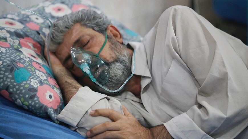 An Iraqi man is treated for breathing difficulties at a Baghdad hospital's emergency ward as choking clouds of dust blanket the Iraqi capital on June 13, 2022 for the tenth time since mid-April