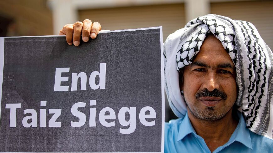 A demonstrator holds a sign in May 2022 demanding the end to the years-long blockade of the Yemeni city of Taez 