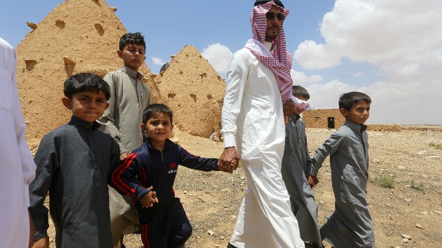 Abdulaziz al-Oqab walks with with his nephews who were orphaned when a landmine exploded under a pick-up truck, claiming the lives of 21 family members