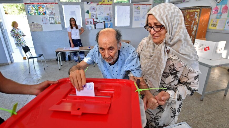 An elderly Tunisian man arrives with his wife to vote in Tunis in a referendum on a draft constitution