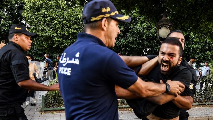 Tunisian policemen arrest a protester during a demonstration during a protest days before  President Kais Saied holds a referendum on a controversial constitution