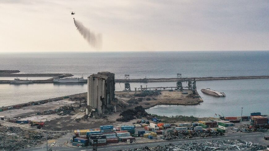 A Lebanese army helicopter releases water over the heavily damaged grain silos at the port of the capital Beirut
