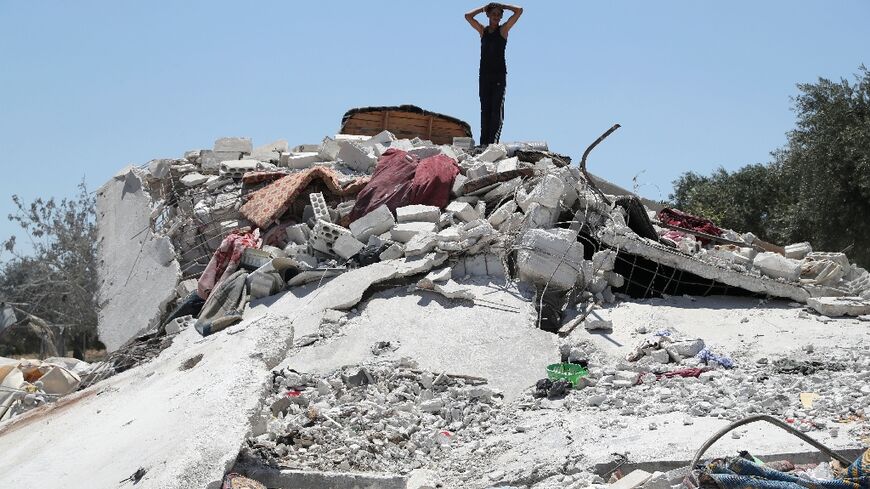 A Syrian youth gestures above debris following a deadly air strike on the outskirts of the rebel-held city of Jisr al-Shughur in Syria's northwestern province of Idlib