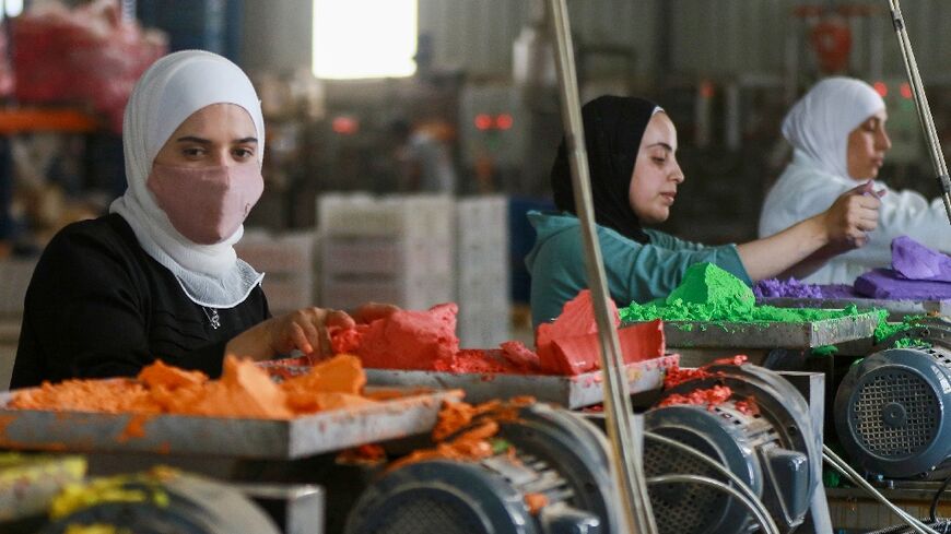 Jordanian workers put coloured chalk through a machine in the factory in Karak, south of the capital Amman 