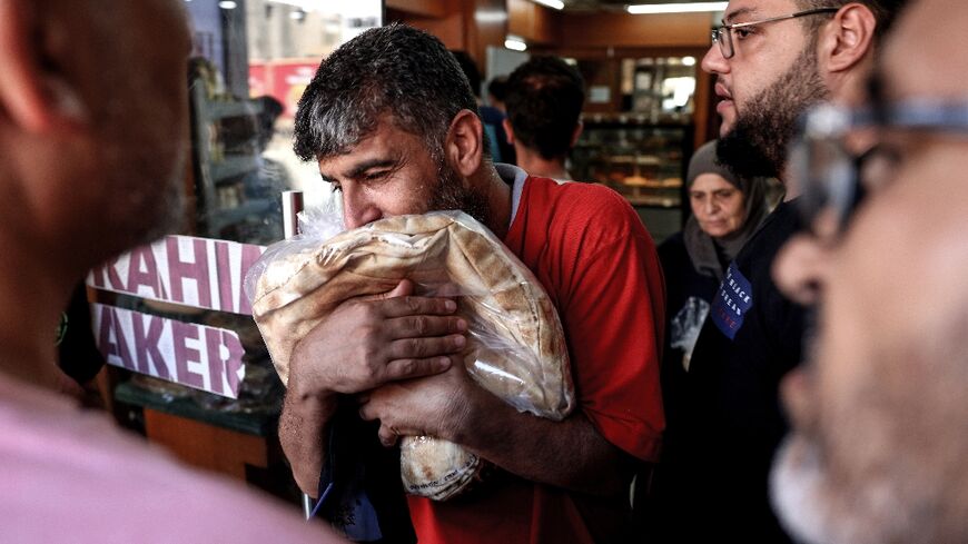 A customer clutches a bag of subsidised flatbread after finally reaching the front of the queue at a a bakery in the Lebanese capital Beirut