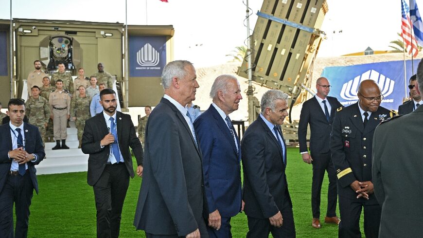 US President Joe Biden (C) walks with Israeli Defence Minister Benny Gantz (L) and caretaker Prime Minister Yair Lapid (2nd R) by an Iron Beam laser defence system (L) and an Iron Dome battery (R) during a tour of the Jewish state's defence systems