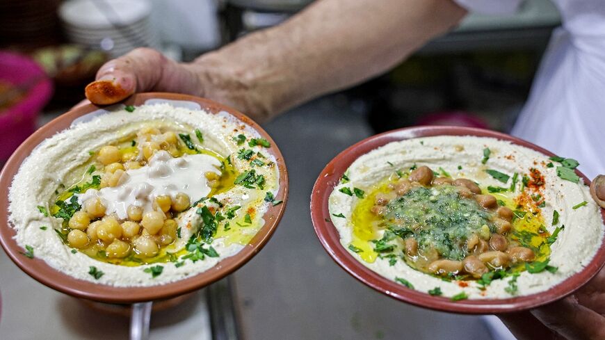 A cook prepares to serve plates of hummus and fava beans at a restaurant in the Old City of Jerusalem