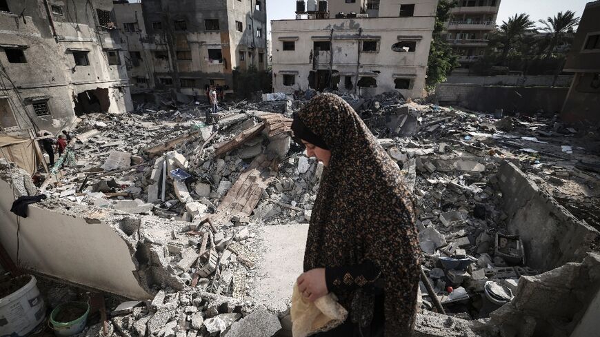 A Palestinian woman walks through rubble in front of her home in Gaza City early on August 8, 2022, following a ceasefire between Israel and Palestinian militants