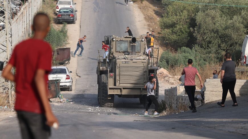 Palestinians  hurl rocks at Israeli army vehicles during clashes in the town of Rujayb, east of the occupied West Bank city of Nablus on August 30