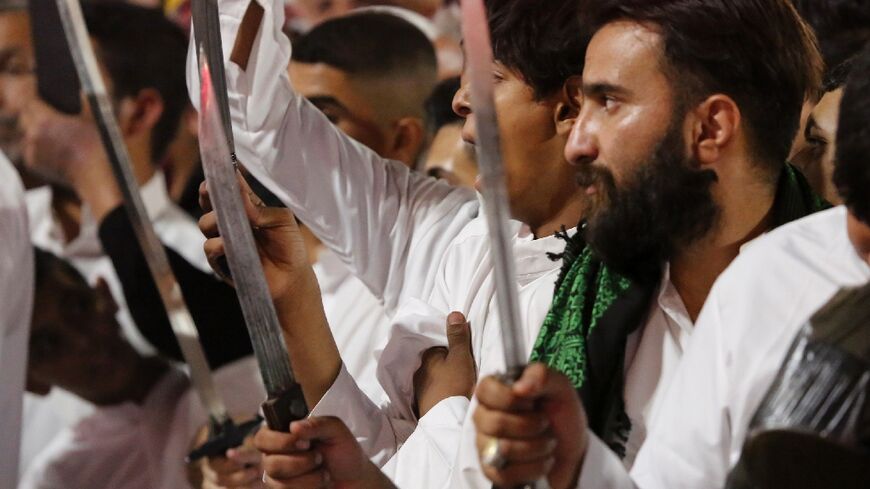 Shiite Muslims brandish knives during the Tatbir processions as they mark Ashura, a 10-day period commemorating the seventh century killing of Prophet Mohammed's grandson Imam Hussein, in Iraq's holy city of Karbala, late on August 8, 2022