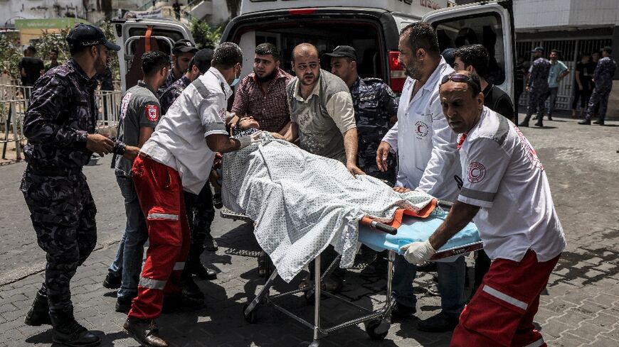 Paramedics rush a Palestinian woman wounded during Israeli air strikes to Shifa hospital in Gaza City on August 6, 2022