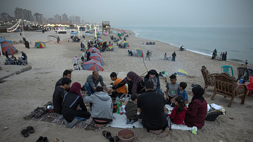 Gazans wait for the sun to set to break their fast on the beach of Gaza City, Gaza Strip, April 29, 2022.