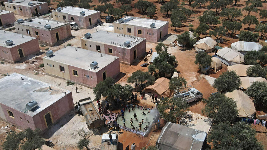An aerial view shows Syrian children playing in a portable swimming pool set up by volunteers, at a camp for the displaced in the rebel-held town of Kafr Yahmul in the northern countryside of Idlib, Syria, Aug. 10, 2022.