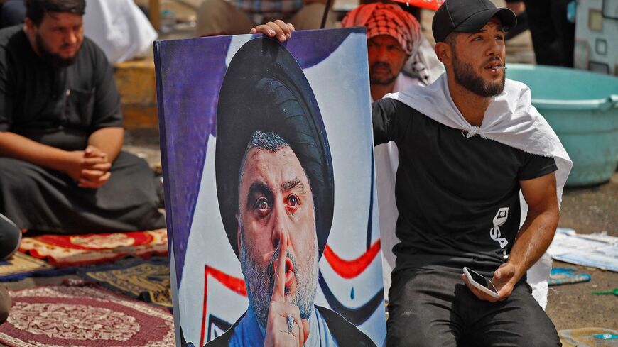 A supporter of Iraqi Shiite cleric Muqtada al-Sadr sits with his portrait during the weekly Friday prayers.