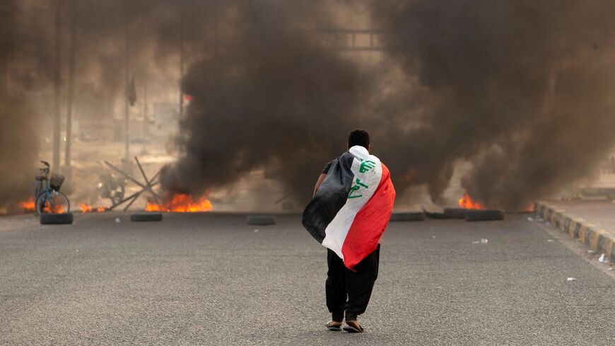 A supporter of Iraqi Shiite cleric Muqtada al-Sadr carries the Iraqi flag.
