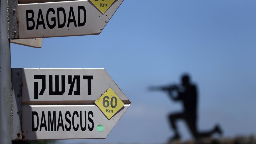 A sculpture of an Israeli soldier standing guard is seen next to a sign for tourists showing the distance to Damascus and Baghdad.