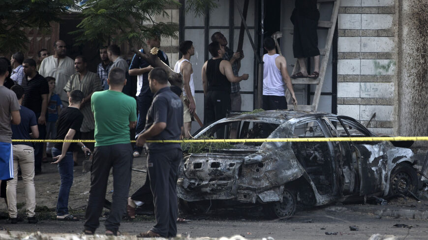 Palestinians gather around a burnt-out car after explosions destroyed five cars belonging to members of Hamas and Islamic Jihad, witnesses and a security source said, Gaza City, Gaza Strip, July 19, 2015.