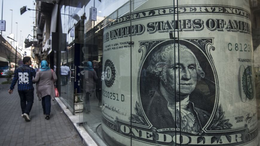 People walk past a currency exchange shop displaying a giant US dollar banknote in downtown Cairo on Nov. 3, 2016. 