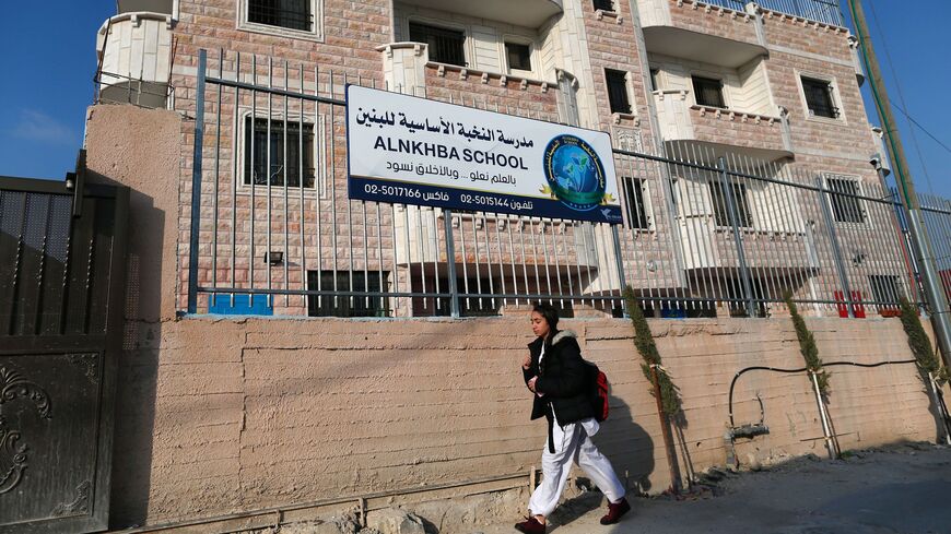 A school girl walks past the Al-Nkhba School.
