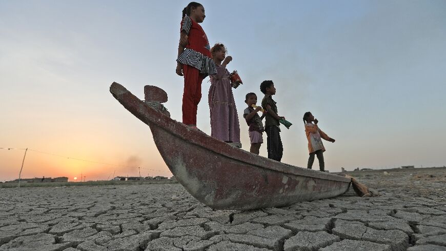 Children stand on a boat lying on the dried-up bed of southern Iraq's receding Chibayish Marshes