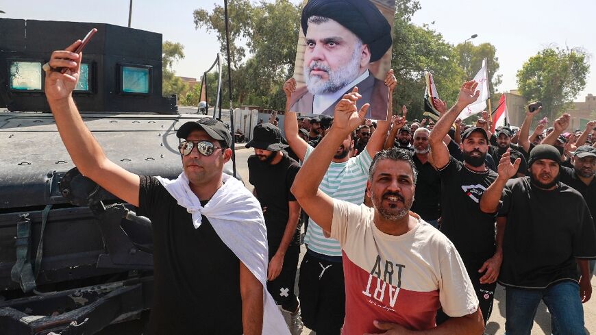 Supporters of the Iraqi cleric Moqtada Sadr raise a portrait of their leader