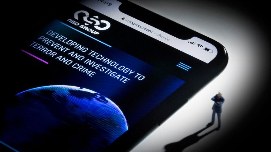 A studio photographic illustration shows the website of NSO Group on a phone -- court documents suggested creditors sought to push the firm to continue selling Pegasus spyware to countries with questionable rights records