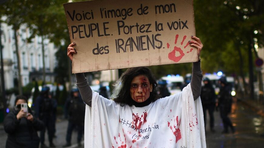 A woman holds a banner reading 'This is the image of my people. Carry the voice of the Iranians' during a demonstration in support of Iranian protesters in Paris on Sunday
