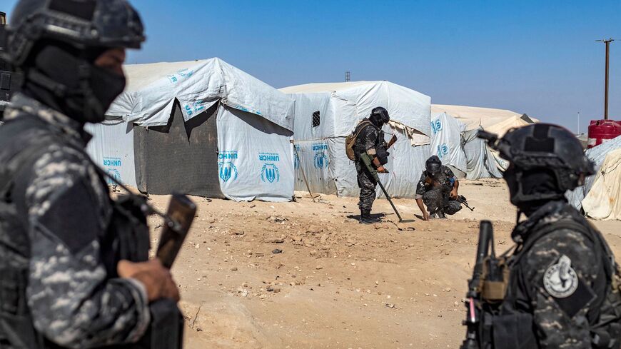 Members of the Syrian Kurdish Asayish security forces use a metal detector to sweep the ground during an inspection of tents at the Kurdish-run al-Hol camp, which holds relatives of suspected Islamic State (IS) group fighters in the northeastern Hasakeh governorate, on Aug. 28, 2022, as the Syrian Democratic Forces mount a security campaign against IS "sleeper cells" in the camp.
