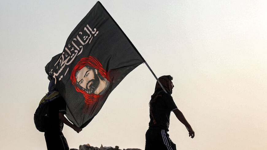 A Shiite Muslim pilgrim marches with a flag bearing the image of Imam Hussein.