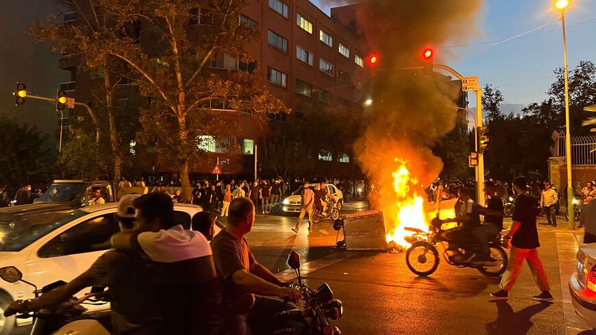 A picture obtained by AFP outside Iran shows demonstrators gathering around a burning barricade during a protest for Mahsa Amini, a woman who died after being arrested by the Islamic republic's "morality police", in Tehran on Sept. 19, 2022.