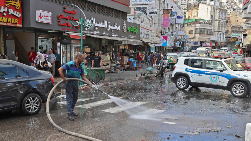 Palestinian men clean a street as calm returns to the city of Nablus following clashes between protesters and Palestinian security forces the previous day, West Bank, Sept. 21, 2022.