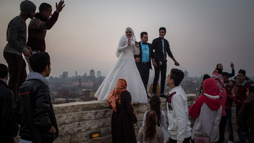 A newlywed couple pose for wedding photos on a wall in a park overlooking Cairo, Egypt, Dec. 10, 2016.