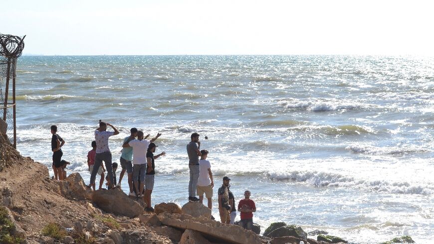 Lebanese men look towards the sea near the Arida border crossing with Syria