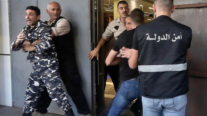 A policeman is stopped by security guards from entering a bank in the Lebanese port city Sidon on September 26 as banks reopened to depositors with scheduled appointments only