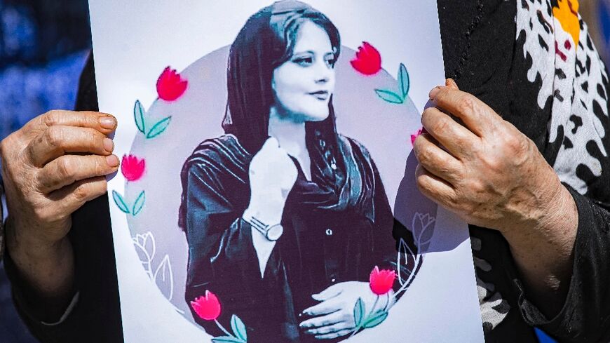 A woman holds up a picture of Mahsa Amini, the young Iranian woman who died while in Iranian police custody, at a solidarity demonstration in Syria's northeastern city of Hasakeh 