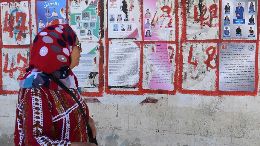 A Tunisian woman looks at posters of candidates for the legislative elections, Tunis, Tunisia, Oct. 4, 2019.