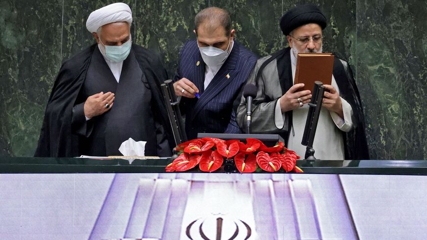 President Ebrahim Raisi (R) kisses the Koran in the presence of Gholam-Hossein Mohseni-Ejeie.