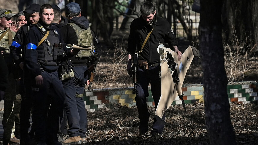 A Ukrainian serviceman carries a downed Russian drone.