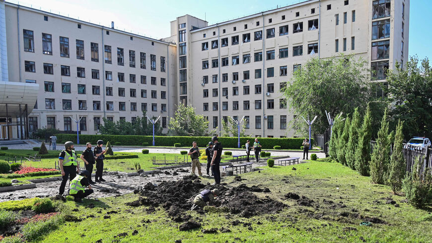 Police experts inspect a crater caused by a shell explosion following a Russian airstrike outside the National University of Urban Economy, Kharkiv, Ukraine, July 23, 2022.