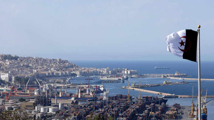 The national flag of Algeria flies near the Bay of Algiers with the old town of the capital known as the "Kasbah" (L) and cargo containers (R) in Algiers, Algeria, Aug. 25, 2022.