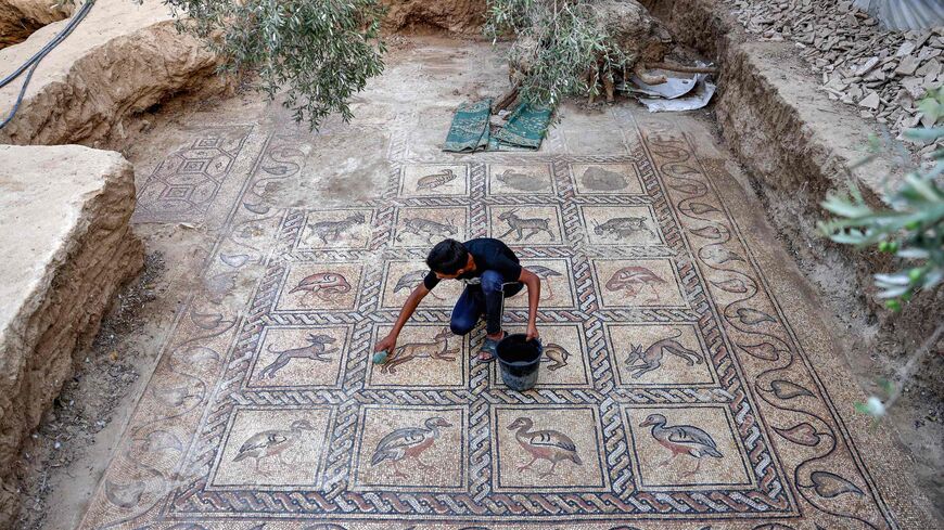The son of Palestinian farmer Salman al-Nabahin uses a sponge to uncover Byzantine mosaics.