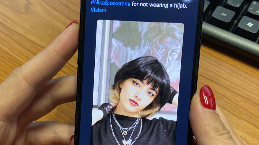 A woman looks at the profile picture of Iranian teenager Nika Shakrami who was reportedly killed recently during protests in Iran.