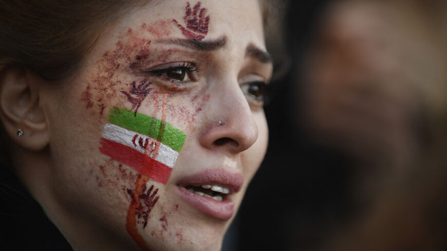 A demonstrator with an Iranian flag and red hands painted on her face attends a rally.