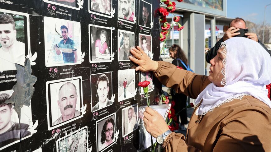 A woman holding a flower touches the picture of a suicide attack victim.