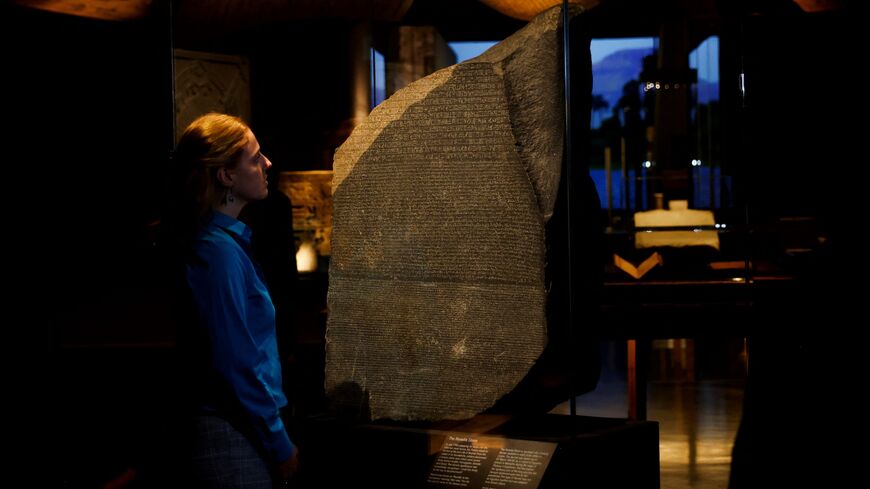 A member of staff looks at the Rosetta stone.