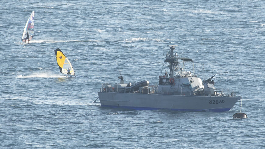 Windsurfers surf by an Israeli navy boat in the Mediterranean Sea at the Israeli side of the border with Lebanon.