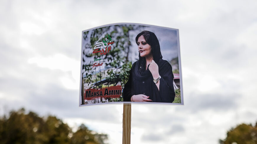 A protester holds a banner with the image of Mahsa Amini as demonstrators gather in front of the Brandenburg Gate to march in solidarity with protesters in Iran, Berlin, Germany, Oct. 15, 2022.