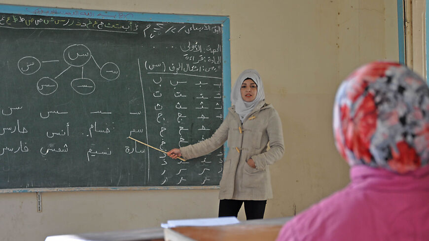 A Syrian teacher shows letters on a board at school in the village of al-Shamatiyah on the ourskirts of Deir ez-Zor, Syria, Feb. 7, 2018.