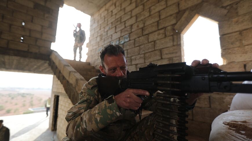 A Turkey-backed Syrian fighter mans a machine gun in a fortified position close to the border with Turkey